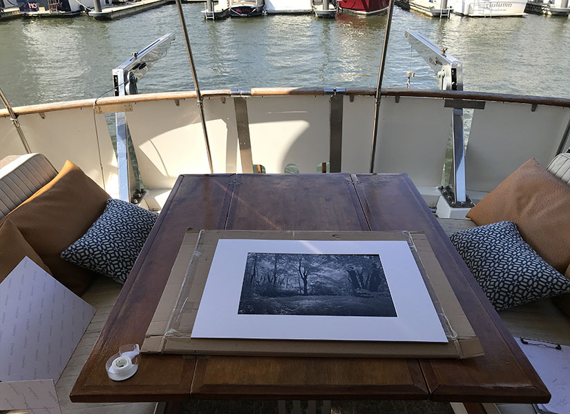 Matted but not yet framed B&W photo on a table on the aft deck of a yacht.